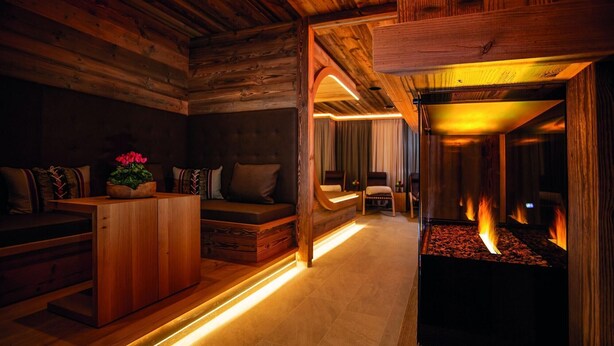 Un interior acogedor de cabaña con paredes y muebles de madera, una chimenea, un sofá y un armario de madera.