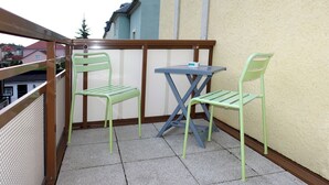 A balcony with two green chairs and a blue table.