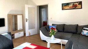 A living room with a grey sofa, a white coffee table, and a painting of a vintage car.