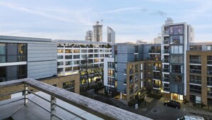 A modern urban residential area with multi-story buildings, balconies, and a parking area.
