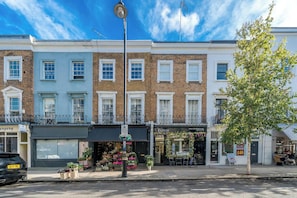 Three-story townhouses with flower shop on the ground floor, offering a charming street scene.