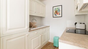 A kitchen with white cabinets, a sink, a toaster, and a trash bin. - JOIVY Pimlico Flat with Terrace for 3 (London)