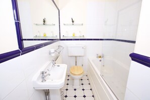 A bathroom with a white sink, wooden toilet, and a bathtub.