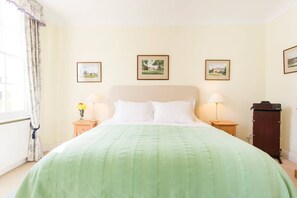 A hotel room with a bed, two bedside tables, a dresser, and three framed pictures on the wall.
