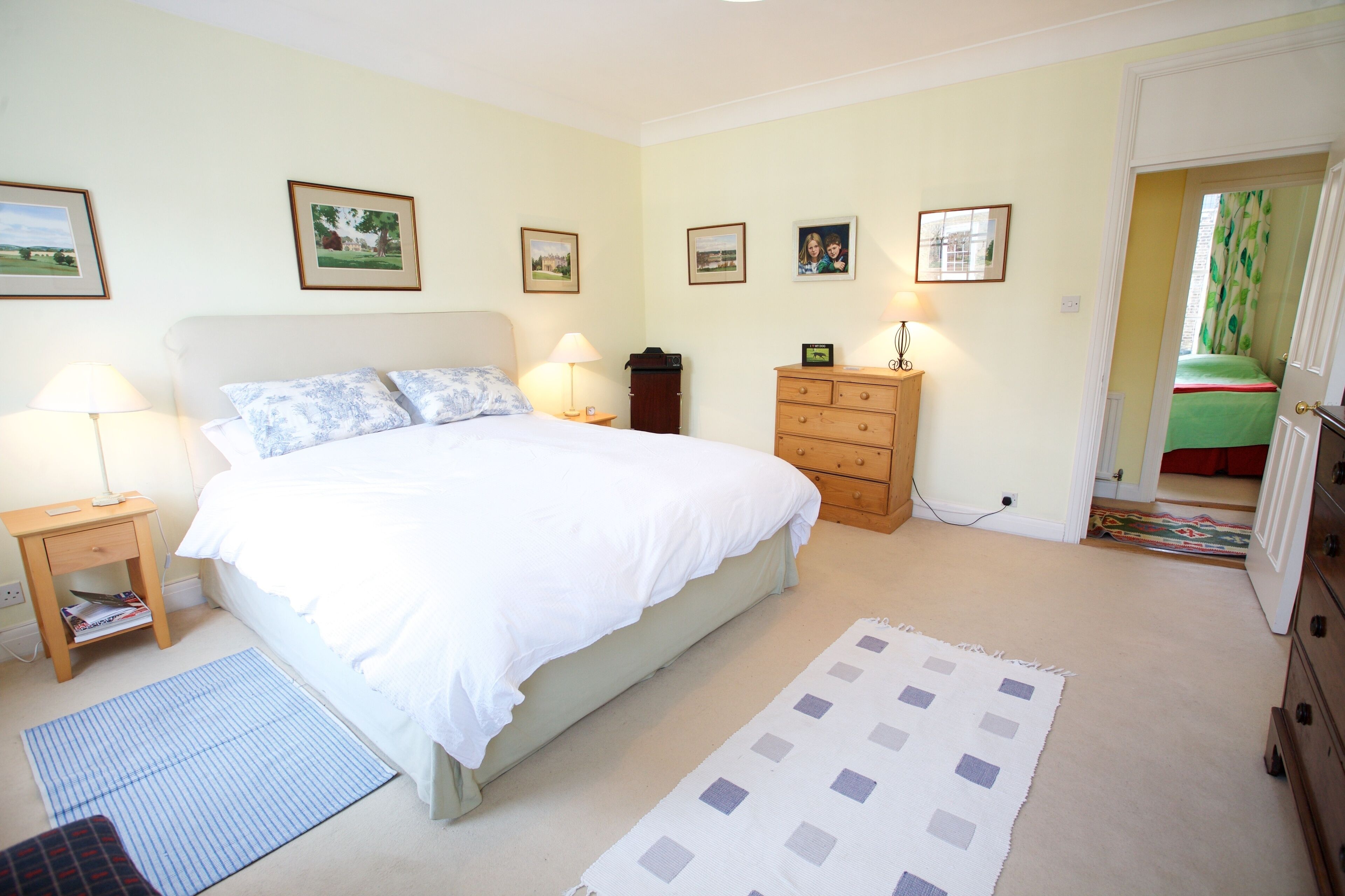A bedroom with a bed, bedside tables, a dresser, and framed pictures on the wall.