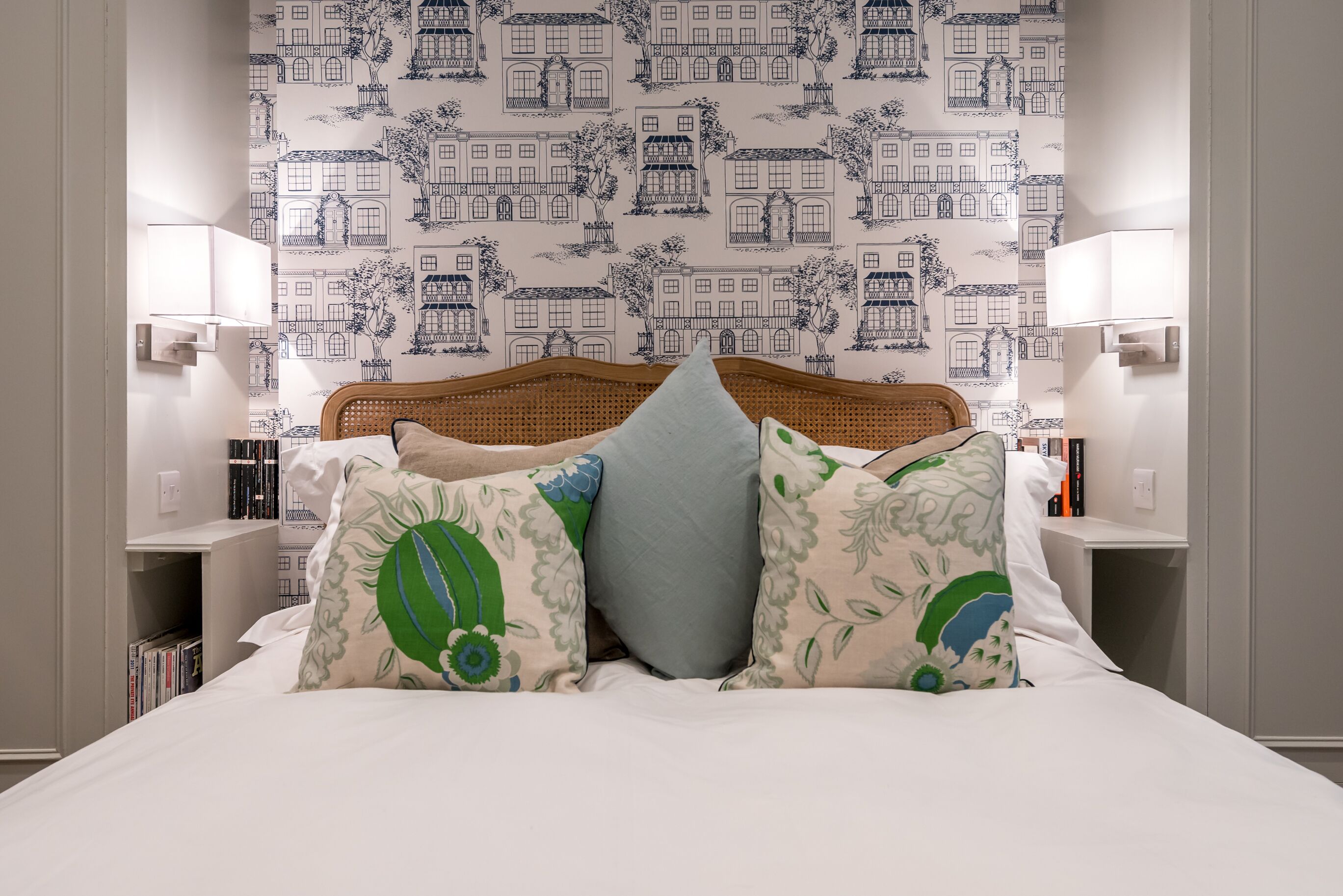 A neatly made bed with patterned pillows, a headboard, and bedside lamps.