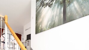 A staircase with white railings and a wooden handrail, leading to a landing with a wall-mounted picture of a forest scene. - JOIVY Splendid 1 Bedroom Flat near St. Paul's Cathedral (London)