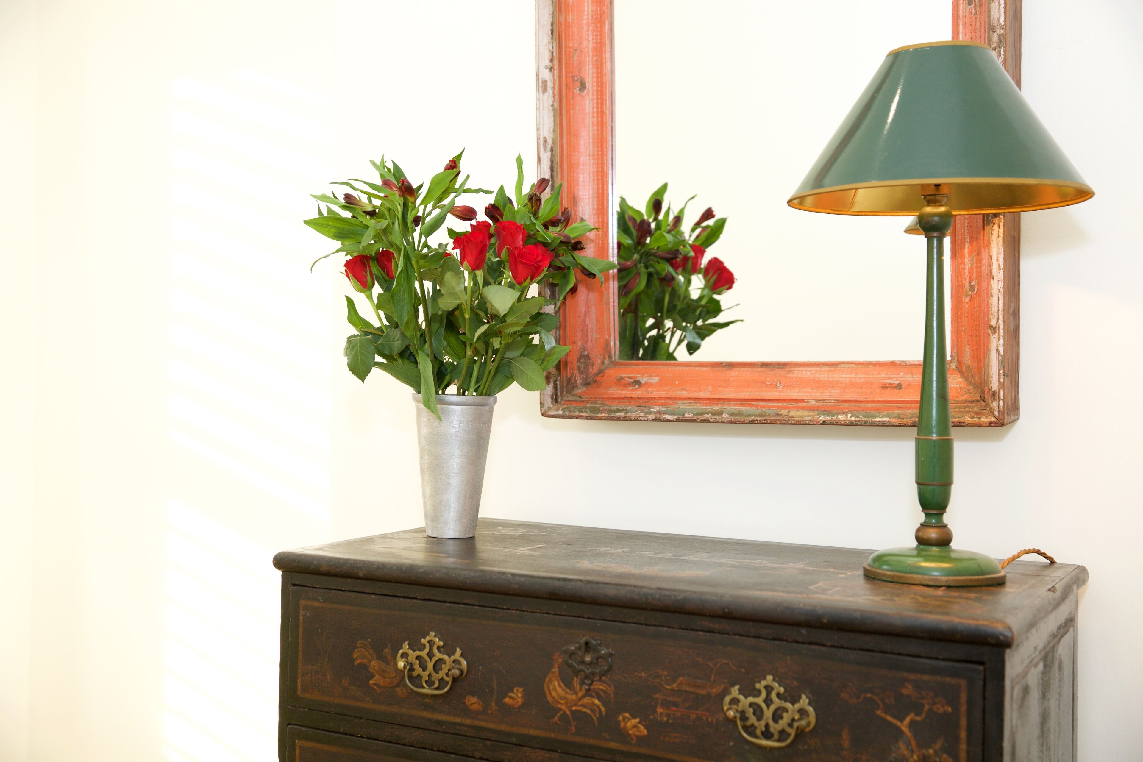 A dresser with a mirror and a lamp.