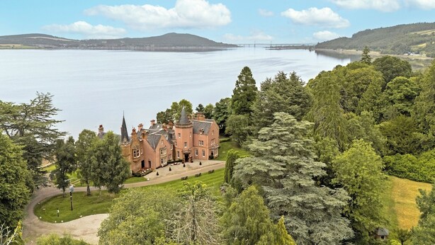 A large, historic building with a symmetrical facade, surrounded by lush greenery and a lake. - Bunchrew House Hotel (Inverness)