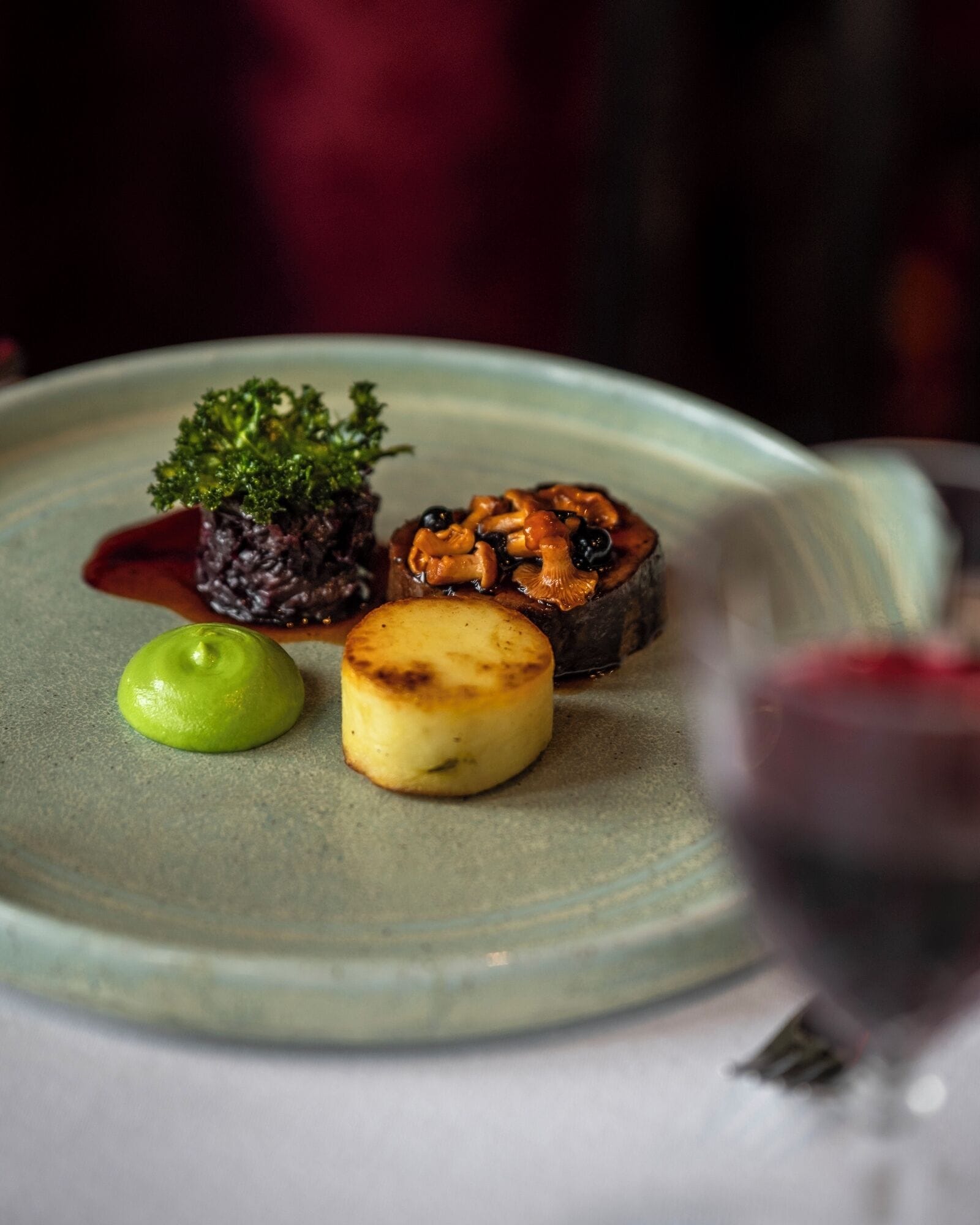 A plate with various dishes and a glass of red wine.