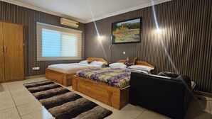 Ein Schlafzimmer mit Bett, Stuhl, Kleiderschrank, einem Fenster mit Jalousien und einem Bild an der Wand.