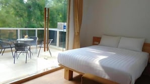 A bedroom with a bed, a window with curtains, and a balcony with chairs and a table. - An Hotel Jakarta (Jakarta)