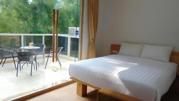 A bedroom with a bed, a window with curtains, and a balcony with chairs and a table. - An Hotel Jakarta (Jakarta)