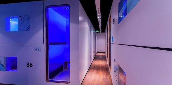 A hallway with a wooden floor, numbered room 36, and a blue-lit door. - An Hotel Jakarta (Jakarta)