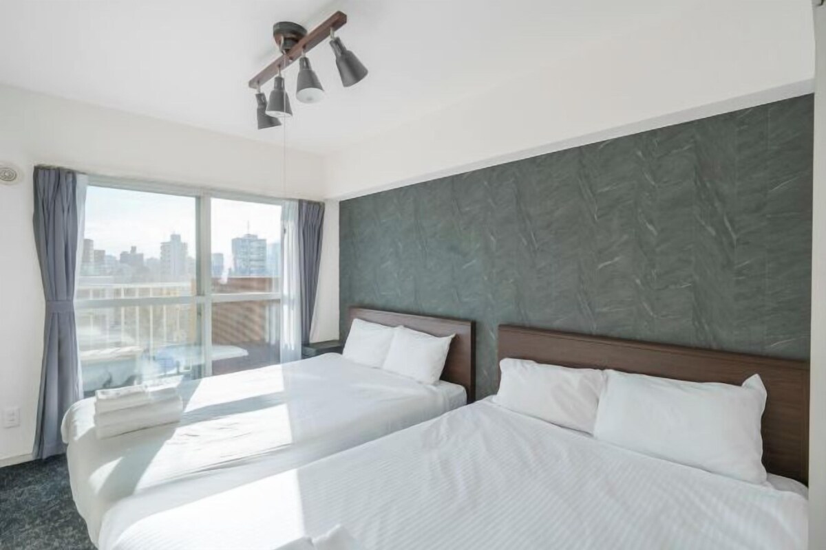A hotel room with two beds, a large window with a city view, and a modern headboard.