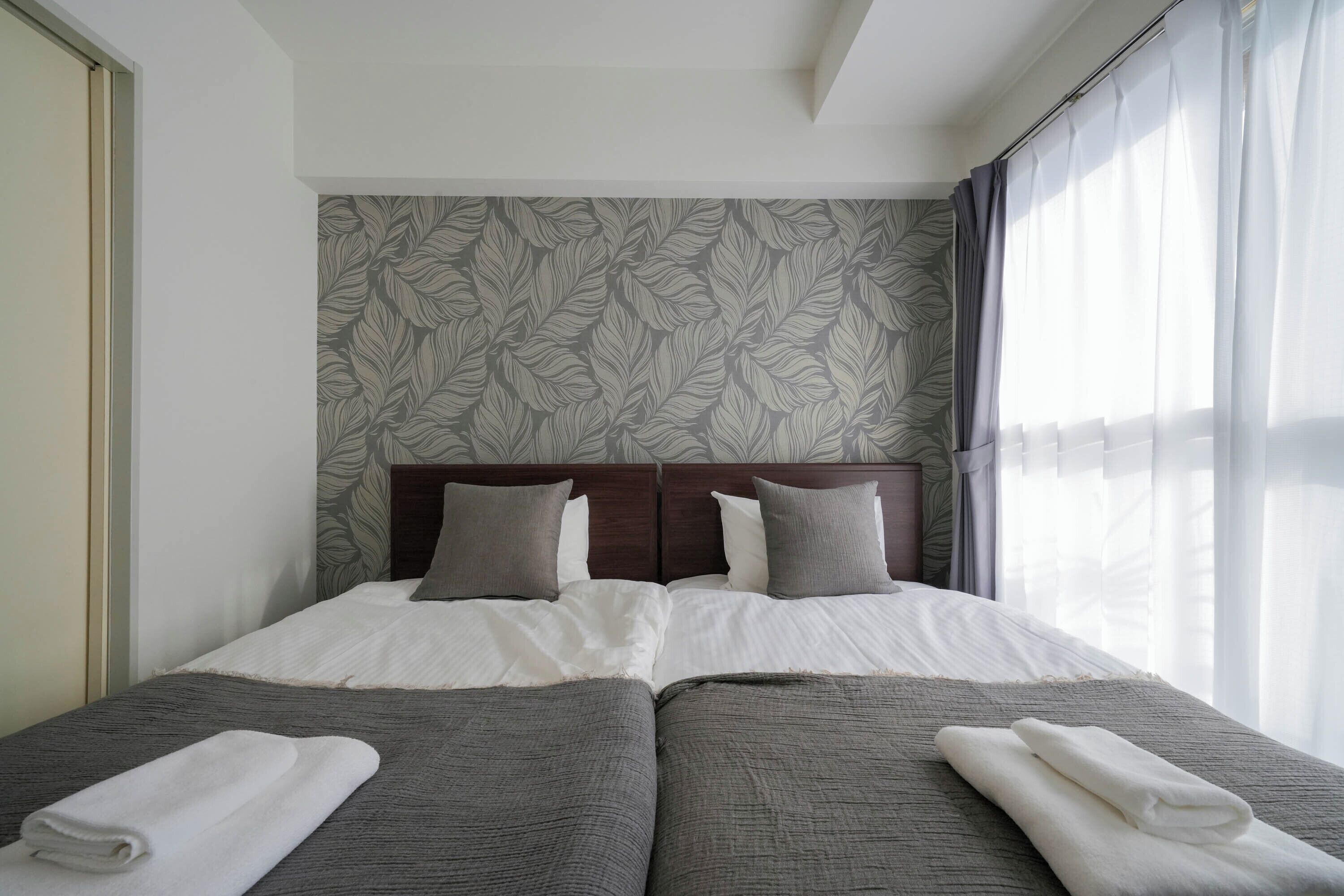 A double bed with a wooden headboard, two pillows, and a grey bedspread.