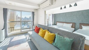 Habitació d'hotel amb un llit gran, un sofà, un balcó amb cortines i vista a la ciutat.