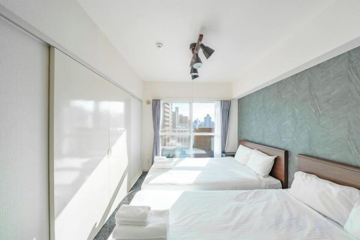 A hotel room with two beds, a large window, and a view of the city.
