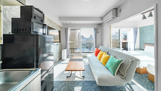 Habitació d'hotel moderna amb bugateria, un sofà amb coixins de colors, taula de fusta petita i una finestra gran amb vista a la ciutat.
