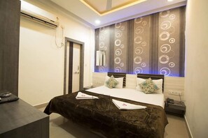 A modern hotel room with a large bed, a desk, and a window with decorative curtains. - Hotel Maa Ganga Palace (Bhopal)
