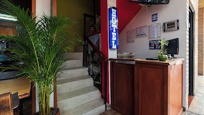 A hotel reception area with a staircase, a reception desk, a potted plant, and a TV screen. - Ayenda 1405 Ibiza (Cali)