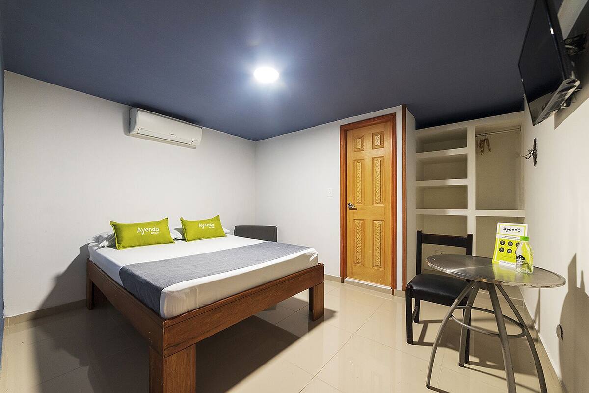 Una camera d'albergo con un letto, una scrivania, una sedia, un armadio e una televisione.