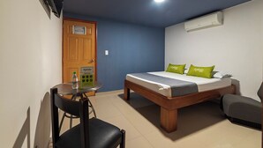 A bedroom with a bed, a chair, a table with a water bottle, and an air conditioning unit. - Ayenda 1405 Ibiza (Cali)