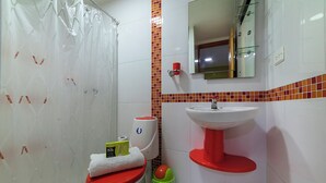 A bathroom with a toilet, a sink, a shower curtain, a mirror, and a tiled backsplash. - Ayenda 1405 Ibiza (Cali)