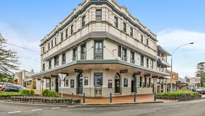 A corner building with multiple signs indicating a restaurant, bar, and accommodation. - Nova Kiama (Wollongong)