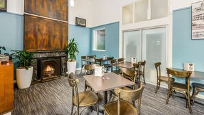 A restaurant with a fireplace, blue walls, and multiple tables and chairs. - Nova Kiama (Wollongong)