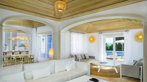 Amplia sala de estar con un sofá blanco, una mesa de centro y un comedor con sillas y una mesa.