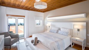 Un dormitorio moderno con una cama grande, una mesita de noche, una silla y vistas al exterior por una puerta corredera.