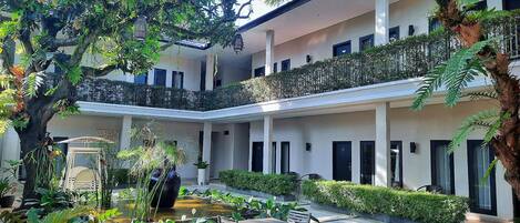 A multi-level courtyard with a central seating area, surrounded by lush greenery and a small water feature.