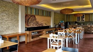 A modern dining area with wooden tables and chairs, a large flat-screen TV, and woven ceiling light fixtures. - Doho Homestay (Jember)