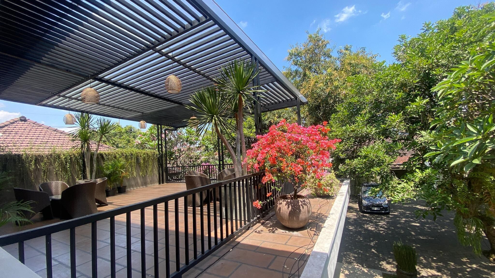 A covered outdoor area with a metal roof, wicker furniture, and potted plants.