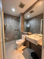 Un baño moderno con cabina de ducha de vidrio, inodoro blanco y tocador con espejo.