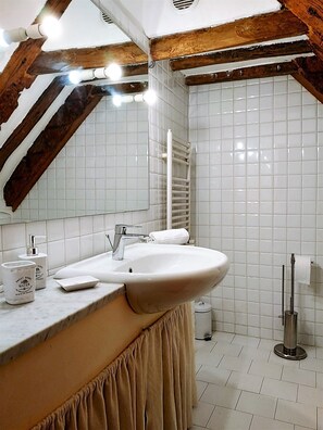 A bathroom with a white sink, mirror, and tiled walls. - City Centre Apartment in Genova grechierco - CasaViva (Genoa)