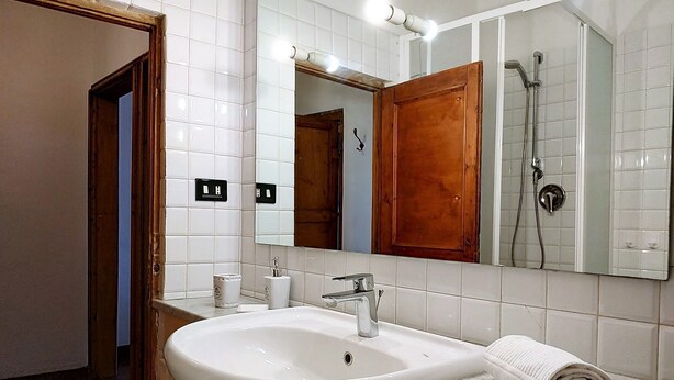 Een badkamer met een wit wastafel, een houten deur en een spiegel boven het aanrecht.