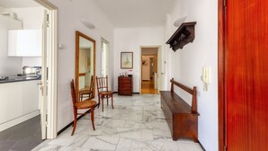 A hallway with a marble floor, wooden furniture, and a red door. - CASAVIVA - PRIMAVERA 1a RAPALLO (Zoagli)