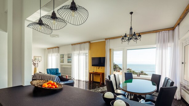 A modern dining area with a round table, chairs, and a view of the sea. - CASAVIVA - PRIMAVERA 1a RAPALLO (Zoagli)
