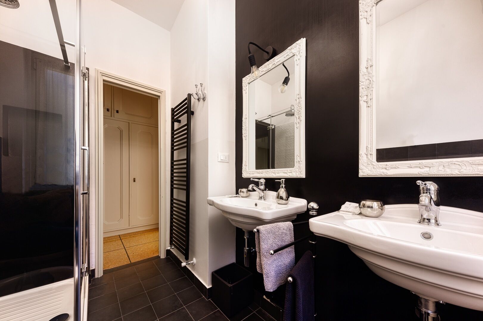A bathroom with two sinks, a mirror, and a shower.