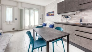 A modern kitchen with a dining area, featuring a grey countertop, blue chairs, and a white dining table. - Casaviva - Val Del Ponte 5 Sanremo (Sanremo)