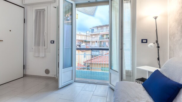 A modern room with a balcony, a white sofa, and a lamp. - Casaviva - Val Del Ponte 5 Sanremo (Sanremo)