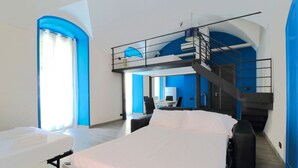 Moderni hotellihuone, jossa on kerrossänky, työpöytä ja portaat.