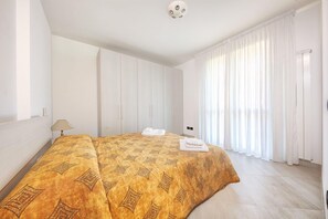 A hotel room with a large bed, a bedside table, and a window with curtains.