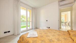 Una habitación de hotel con una cama grande, un balcón con cortinas y un equipo de aire acondicionado.