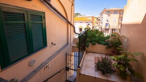 A narrow balcony with green shutters, potted plants, and a view of neighboring buildings. - CasaViva - Mameli 26 Imperia (Imperia)