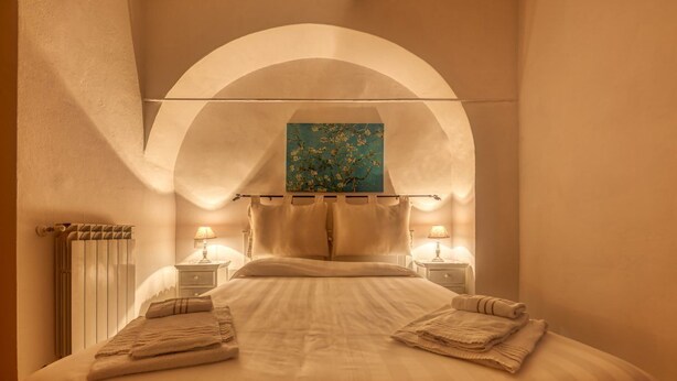 A hotel room with a large bed, two bedside lamps, a painting above the bed, and a radiator on the left. - CasaViva - Mameli 26 Imperia (Imperia)