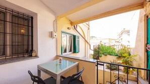 A small balcony with a table and chairs, a window with shutters, and a view of the neighborhood. - CasaViva - Mameli 26 Imperia (Imperia)