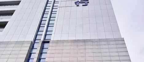 Un bâtiment moderne avec une enseigne bien visible indiquant la présence d’une banque et d’un hôtel.